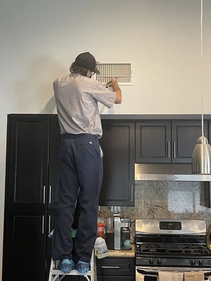 Technician inspecting an air vent during HVAC service in New Franklin